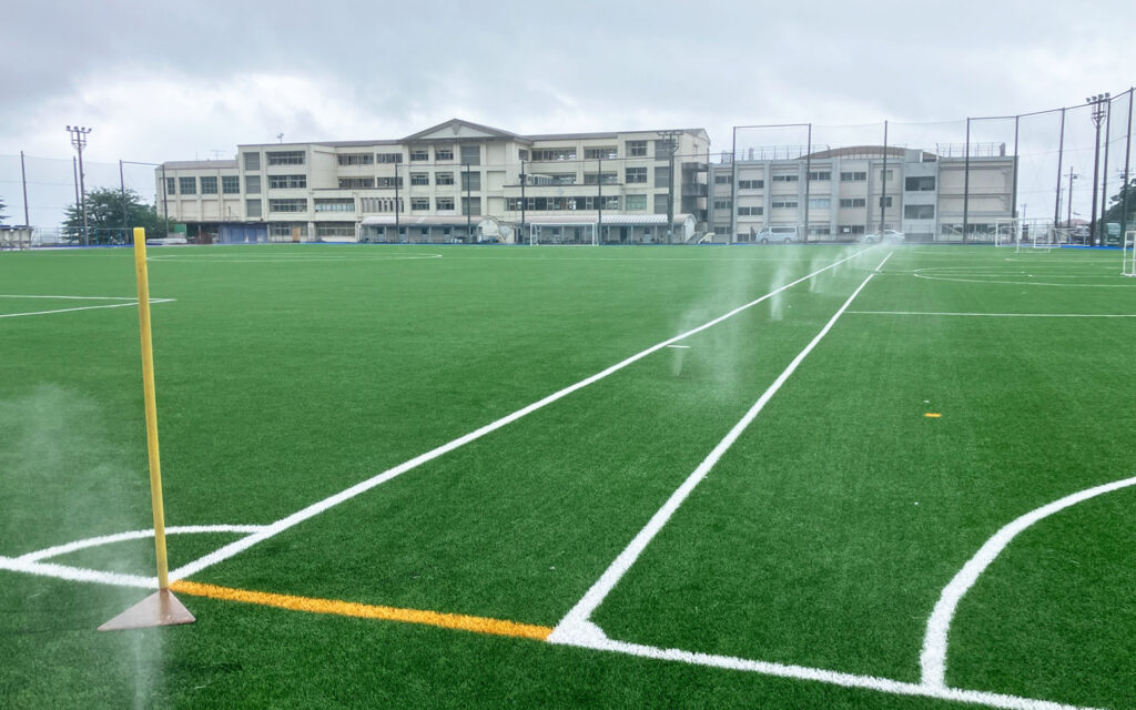 サッカーピッチの周囲にフィールド冷却細霧システムが噴霧される