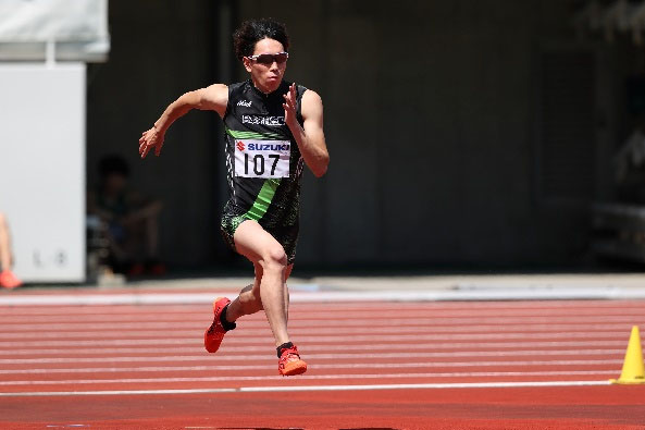 ユニフォーム着用の短距離走選手の競技中の様子