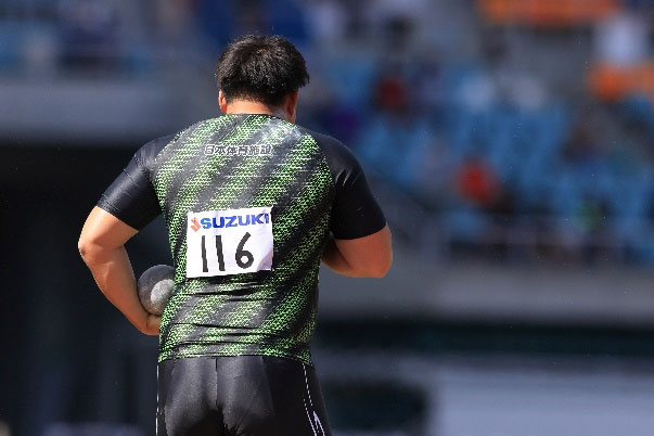 ユニフォーム着用の砲丸投選手の競技中の様子