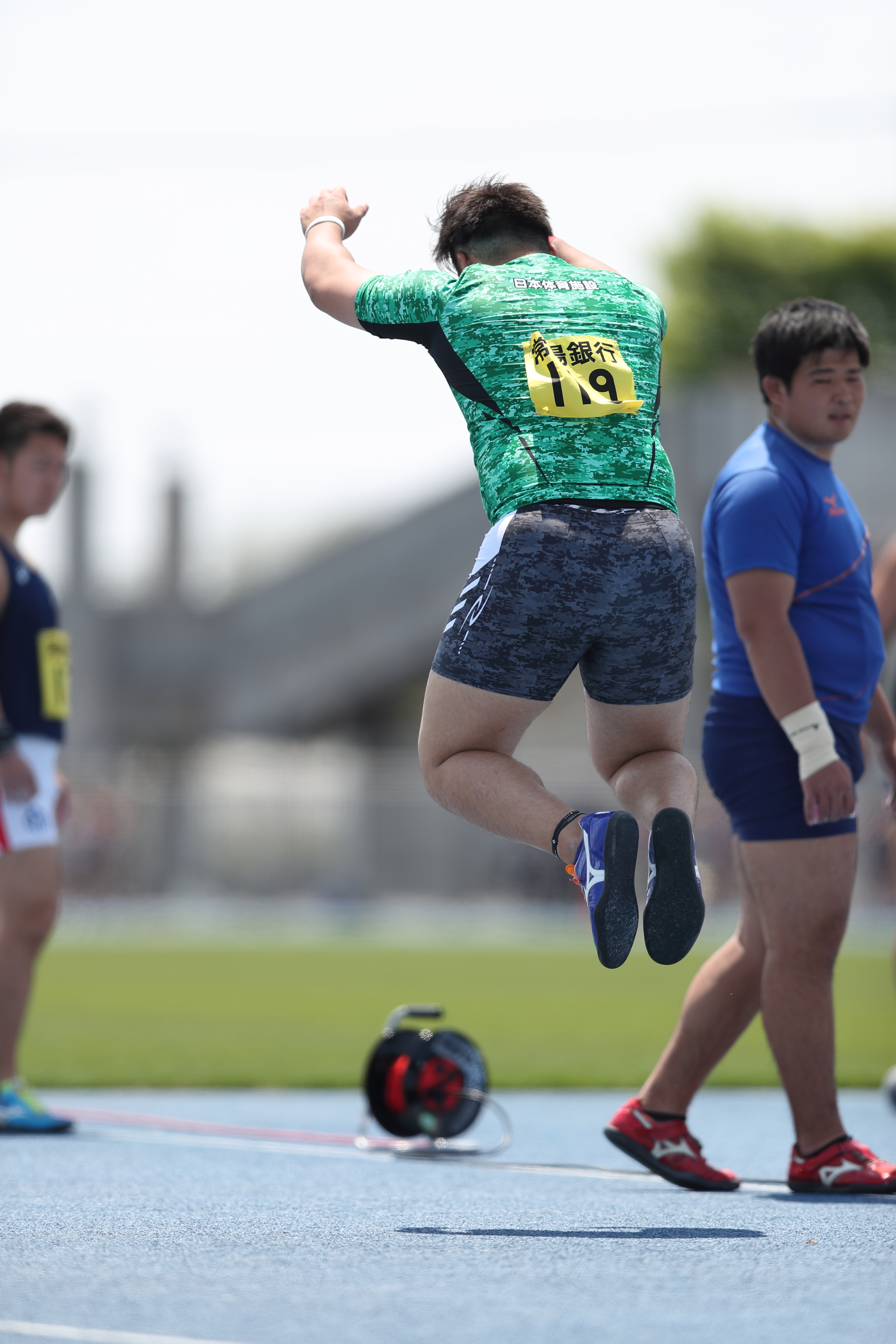 踏み切り動作で跳び上がる砲丸投選手の様子