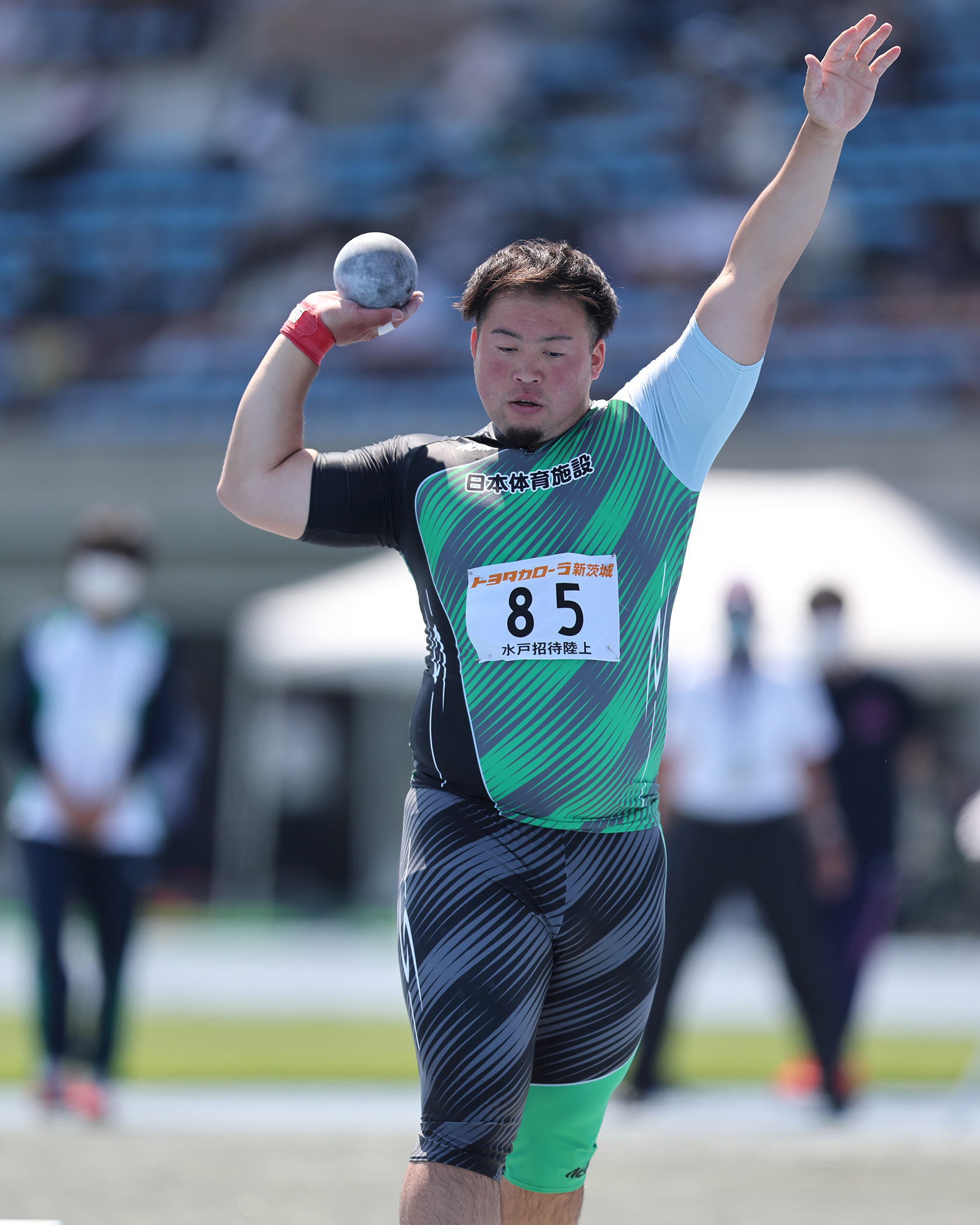 ユニフォーム着用の砲丸投選手の競技中の様子