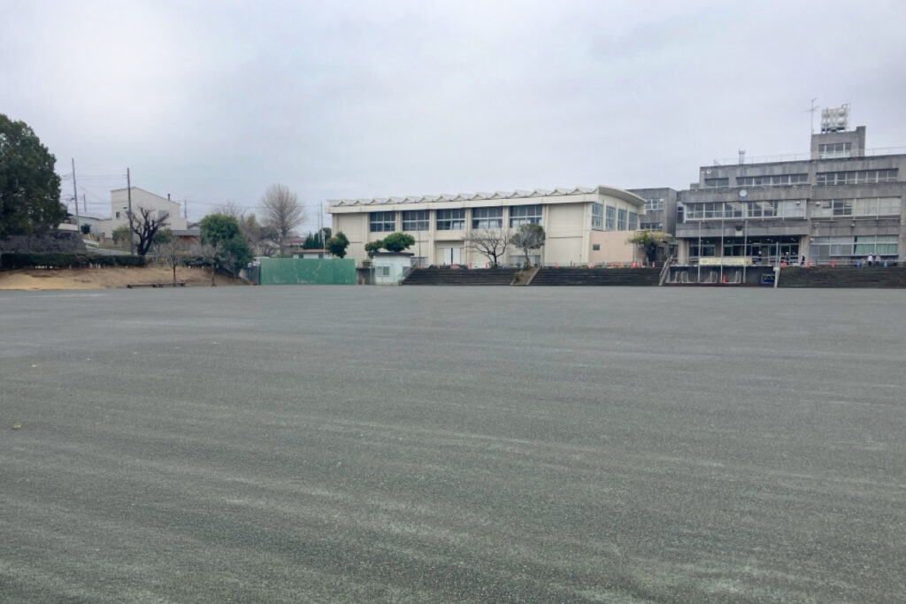 緑色がかったグレーの土と校舎