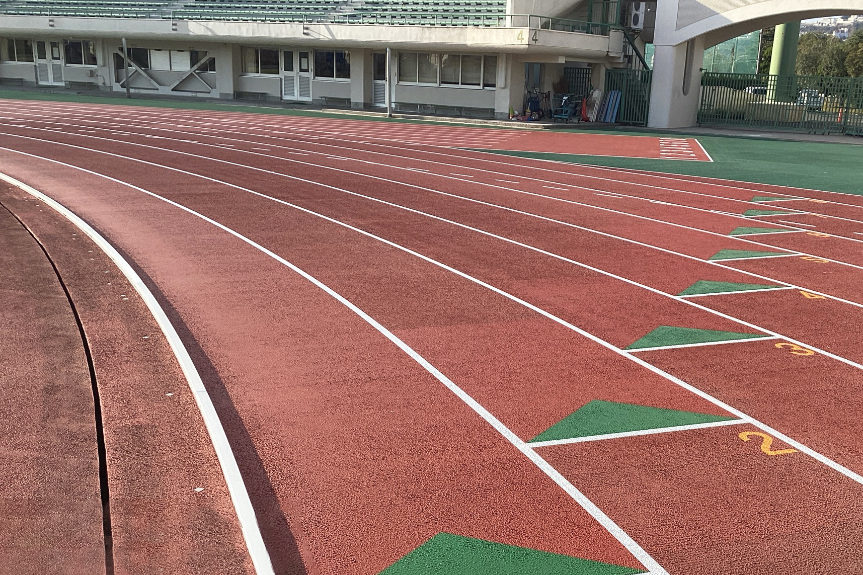 赤色の８レーンの全天候走路、400ｍリレーゾーンの入りを示す三角マークが並ぶ