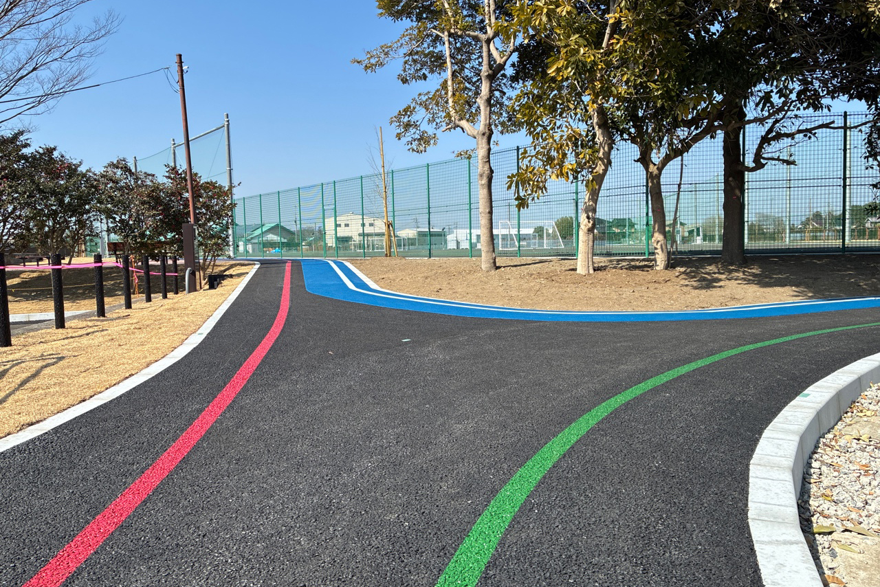 赤と緑いろのラインの入った園路、奥に青い園路が見える