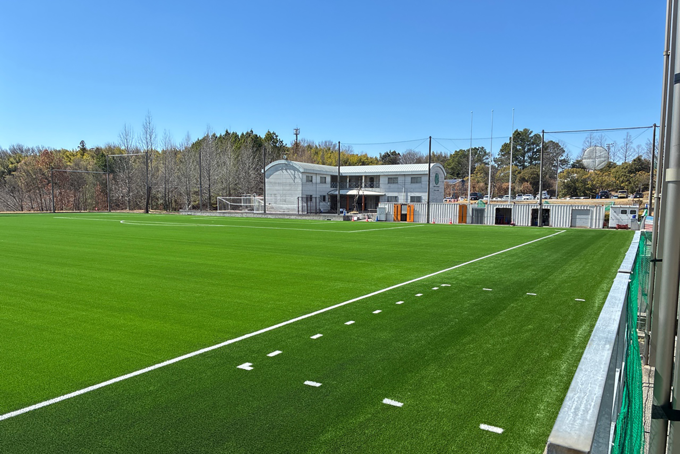 奥に建物がある人工芝のサッカーピッチ
